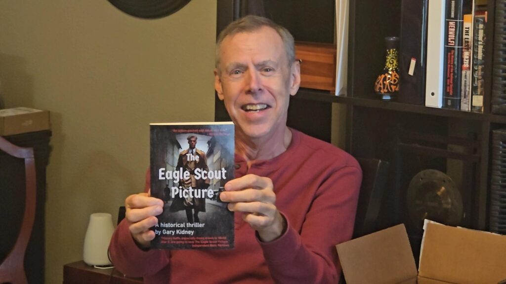 Gary Kidney revealing the cover of The Eagle Scout Picture, a WWII historical spy drama and thriller